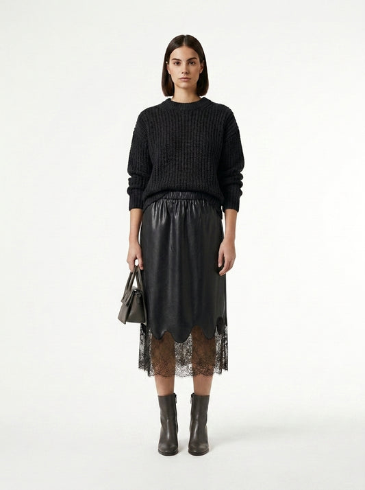 Woman wearing a black sweater and black skirt with lace overlay on a white background