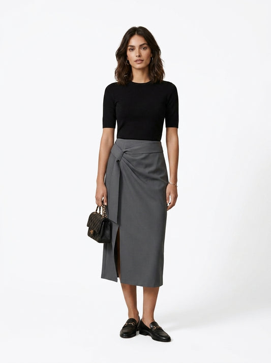 Woman wearing a black top and gray skirt with a white background