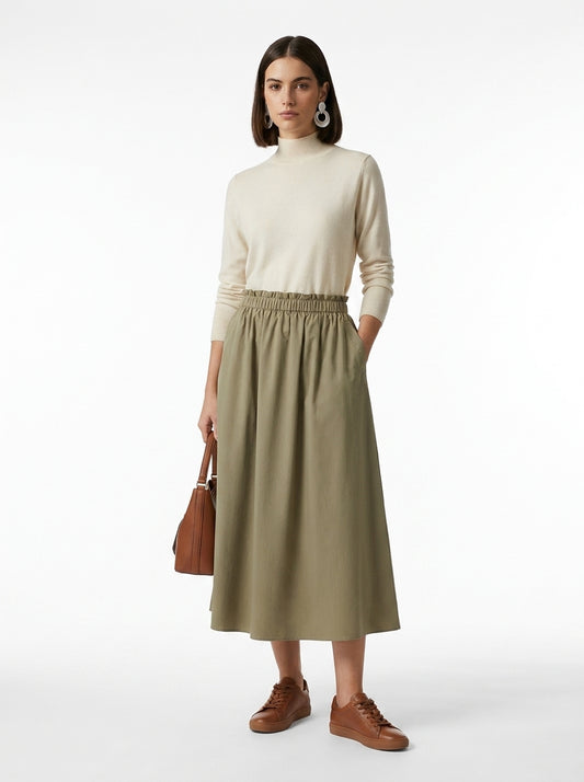 Woman wearing a beige turtleneck and green skirt with brown shoes on a white background