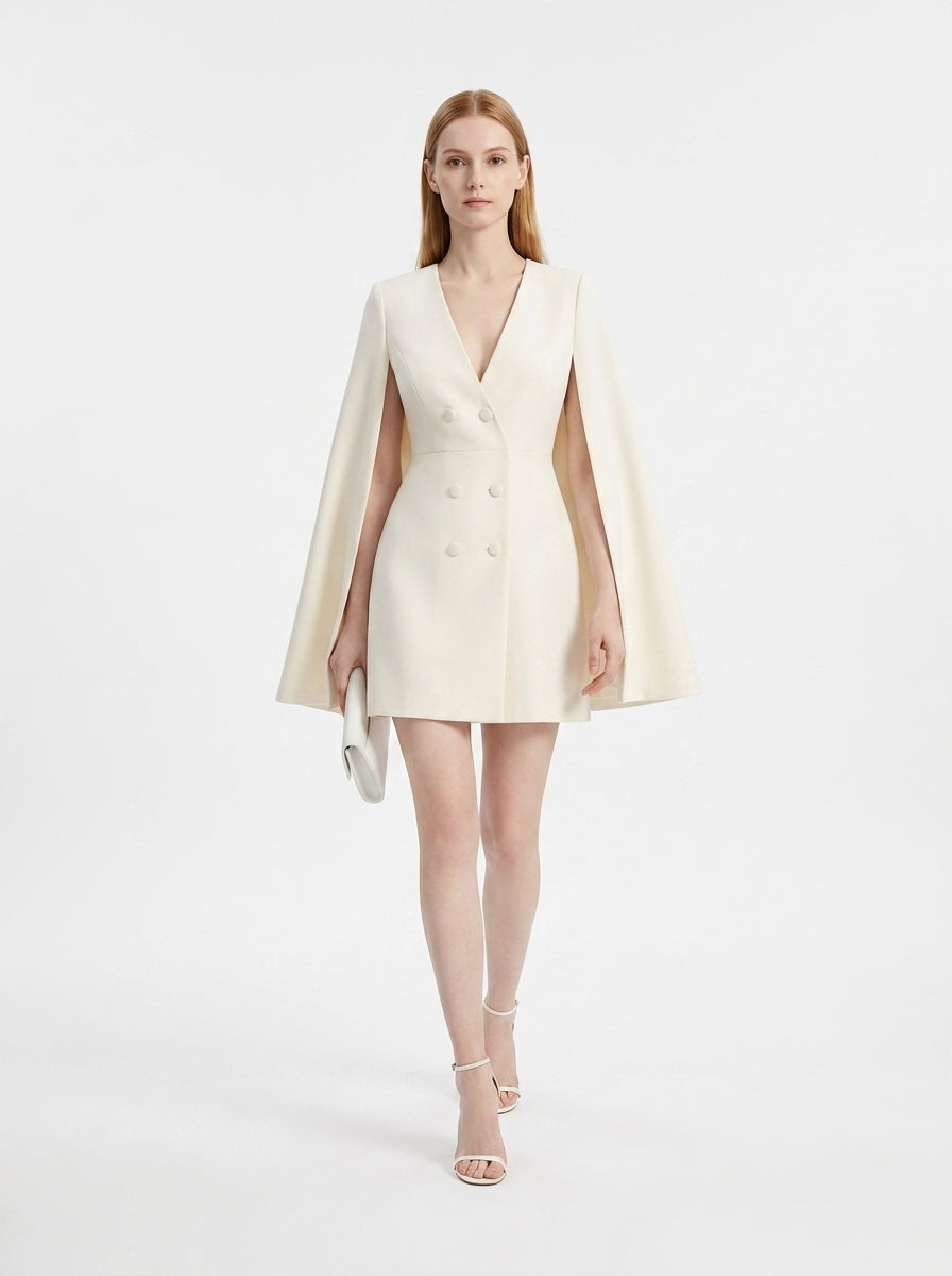 Woman wearing a cream-colored cape dress on a white background