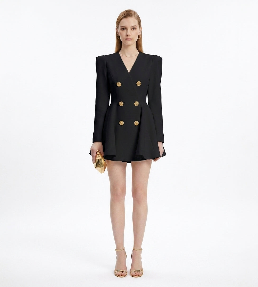 Woman wearing a black blazer dress with gold buttons on a white background
