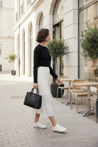 Woman walking on a city street holding a black handbag.