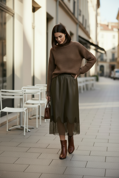 Woman in a brown sweater and green skirt walking on a city street.