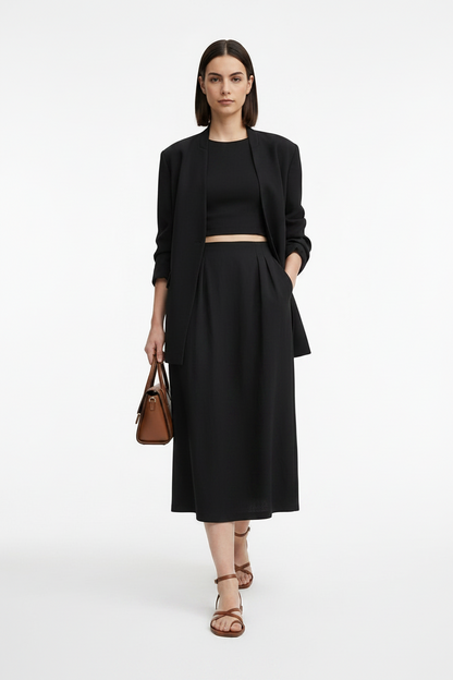 Woman wearing a black outfit with a jacket, top, and skirt on a white background