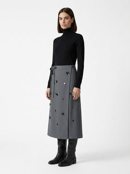 Woman wearing a long gray coat with black buttons on a white background