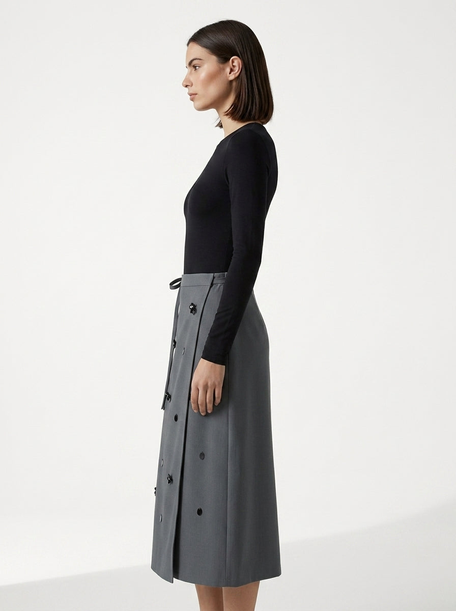 Woman wearing a black top and gray skirt on a white background