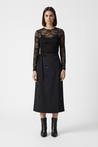Woman wearing a black lace top and black skirt on a white background