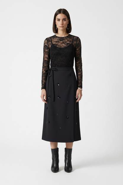 Woman wearing a black lace top and black skirt on a white background