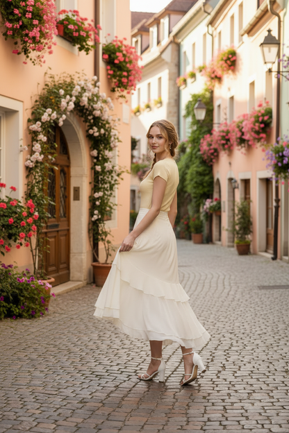 Woman in a yellow dress standing on a cobbled street with floral decorations.