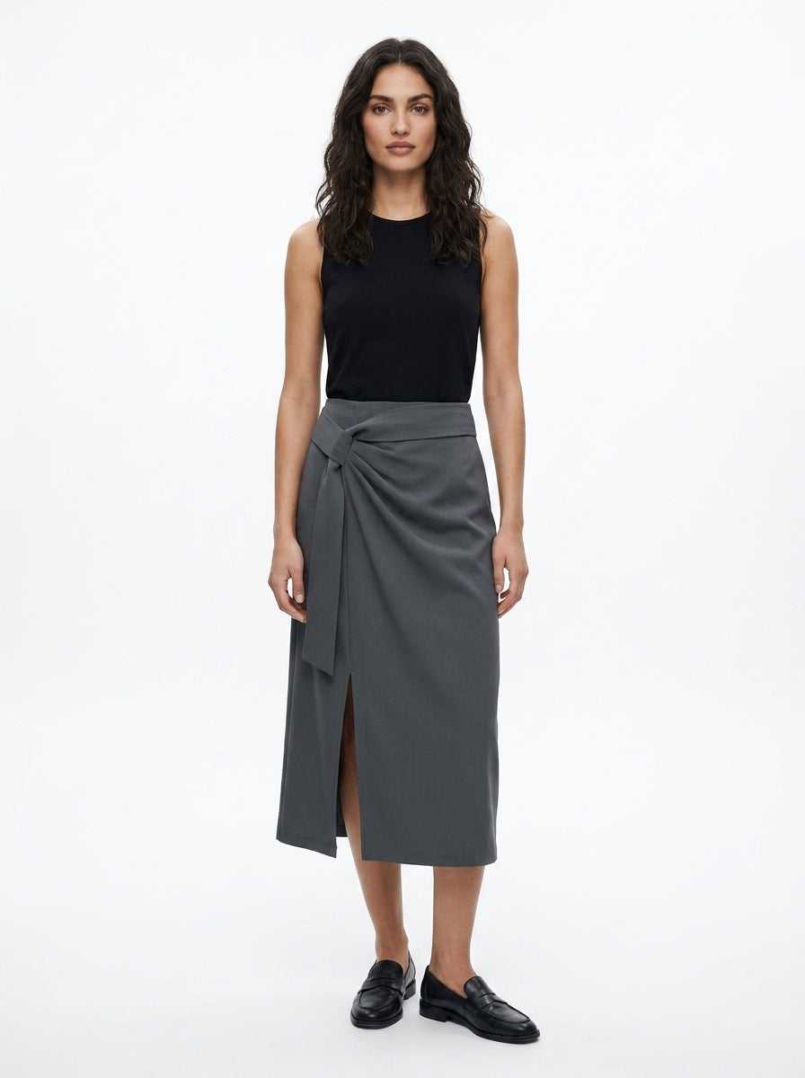Woman wearing a black sleeveless top and gray wrap skirt on a white background