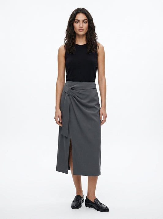 Woman wearing a black sleeveless top and gray wrap skirt on a white background