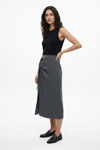 Woman wearing a black sleeveless top and gray skirt on a white background