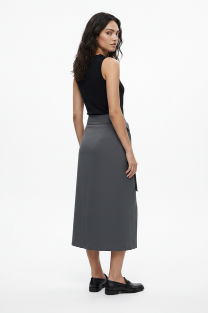 Woman wearing a black sleeveless top and gray skirt on a white background
