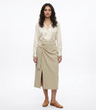 Woman wearing a cream blouse and beige wrap skirt on a white background