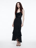 Woman wearing a black dress with ruffled layers on a white background