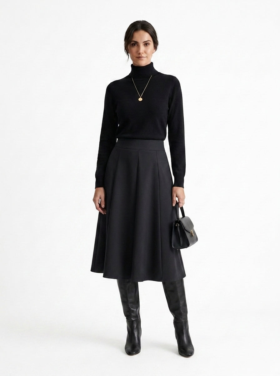 Woman wearing a black turtleneck, black skirt, and black boots on a white background
