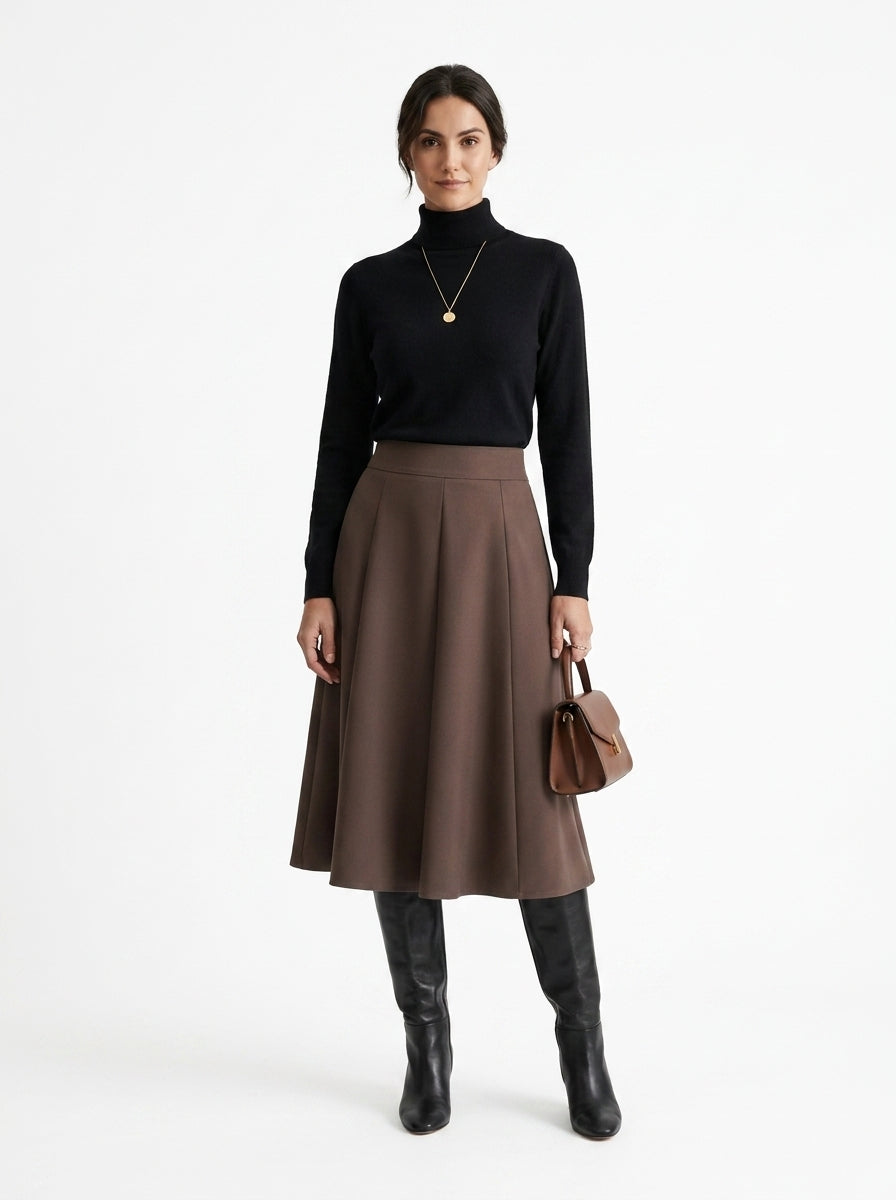 Woman wearing a black turtleneck, brown skirt, and black knee-high boots on a white background