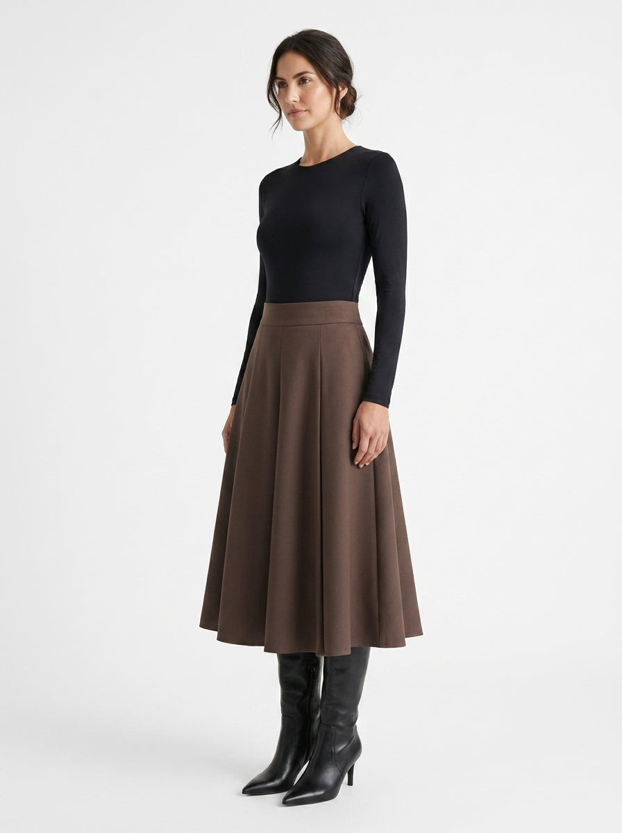 Woman wearing a black long-sleeve top and brown skirt on a white background