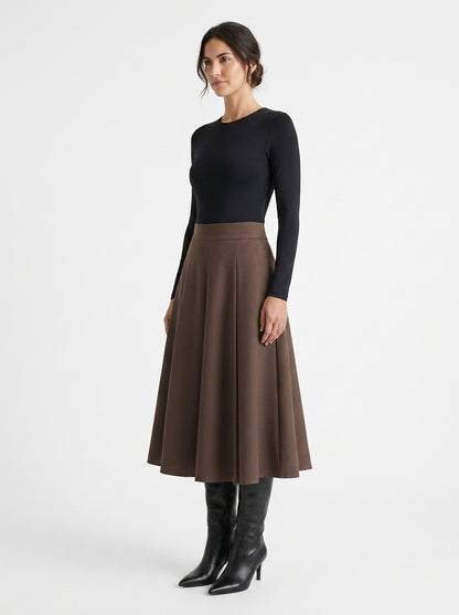 Woman wearing a black long-sleeve top and brown skirt on a white background
