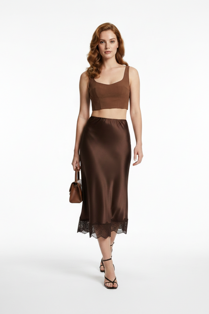 Woman wearing a chocolate satin skirt and top on a white background