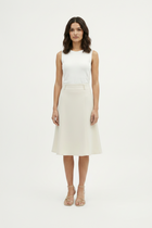 Woman wearing a white sleeveless top and beige skirt on a white background
