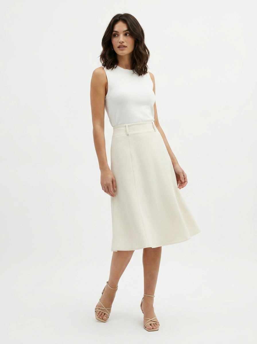 Woman wearing a white sleeveless top and cream-colored skirt on a white background