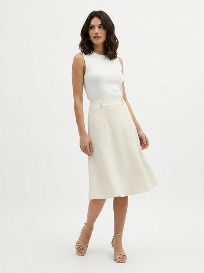 Woman wearing a white sleeveless top and cream-colored skirt on a white background