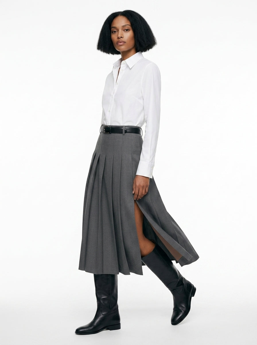 Woman wearing a white shirt, gray skirt, and black knee-high boots on a white background