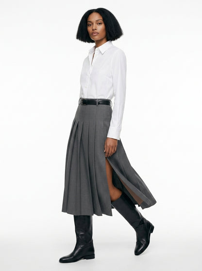Woman wearing a white shirt, gray skirt, and black knee-high boots on a white background