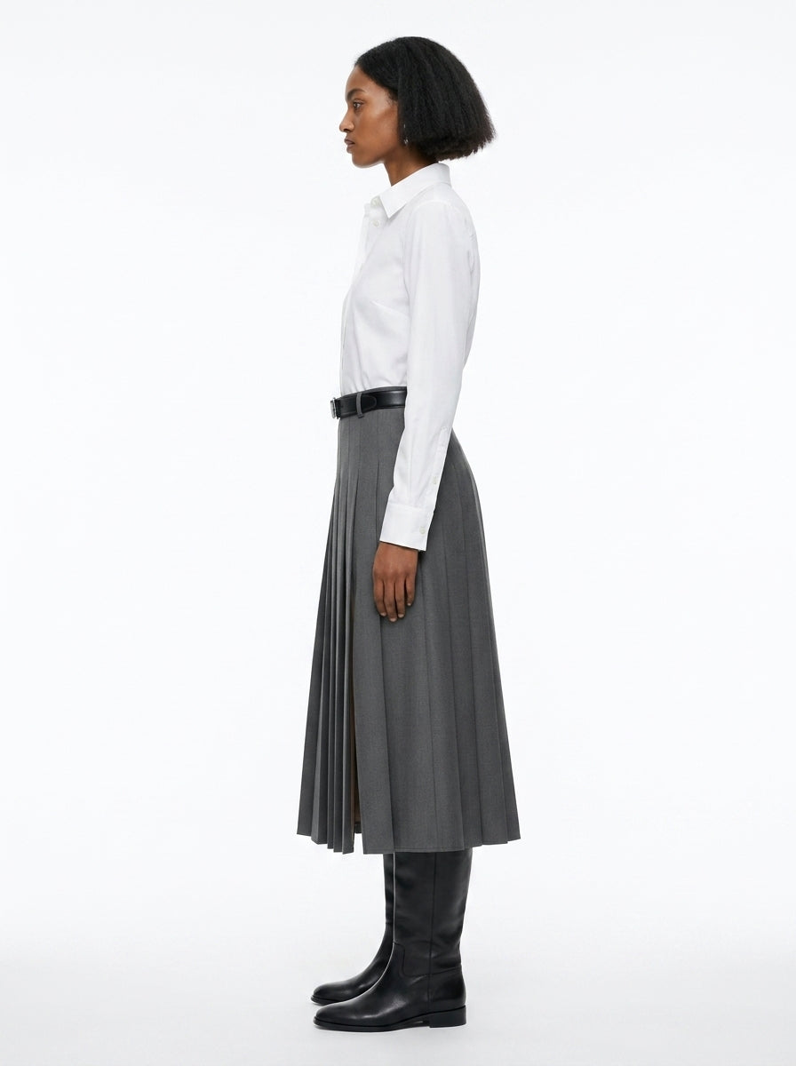 Person wearing a white shirt, gray pleated skirt, and black knee-high boots on a white background