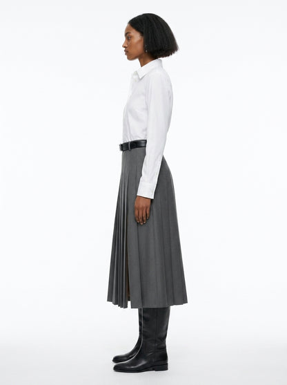 Person wearing a white shirt, gray pleated skirt, and black knee-high boots on a white background