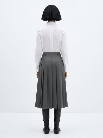 Person wearing a white shirt and gray skirt on a white background