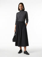 Woman wearing a gray turtleneck dress with a black skirt on a white background