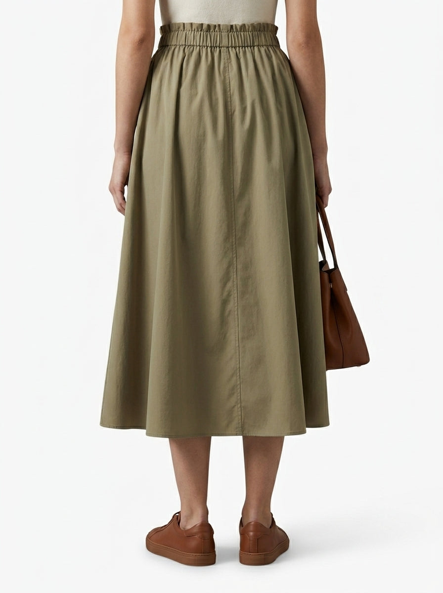 Person wearing a green skirt with brown shoes and a brown bag on a white background