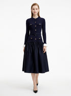 Woman wearing a navy blue dress with a belt on a white background
